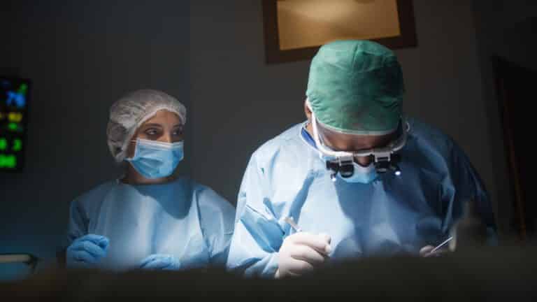 Chirurgien-dentiste et assistante en tenue de bloc pendant une intervention de chirurgie dentaire