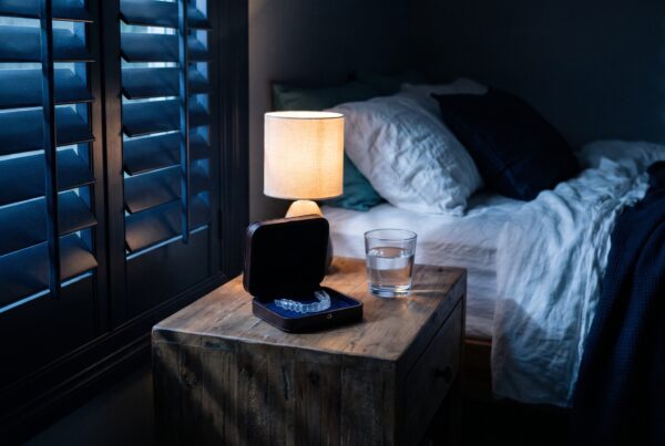 Table de chevet la nuit, gouttière de nuit dans son étui, lumière des persiennes