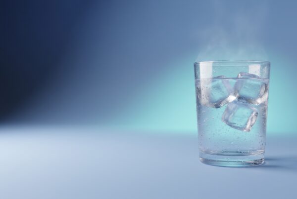 Verre d'eau glacée avec glaçons sur fond bleu nuit et turquoise